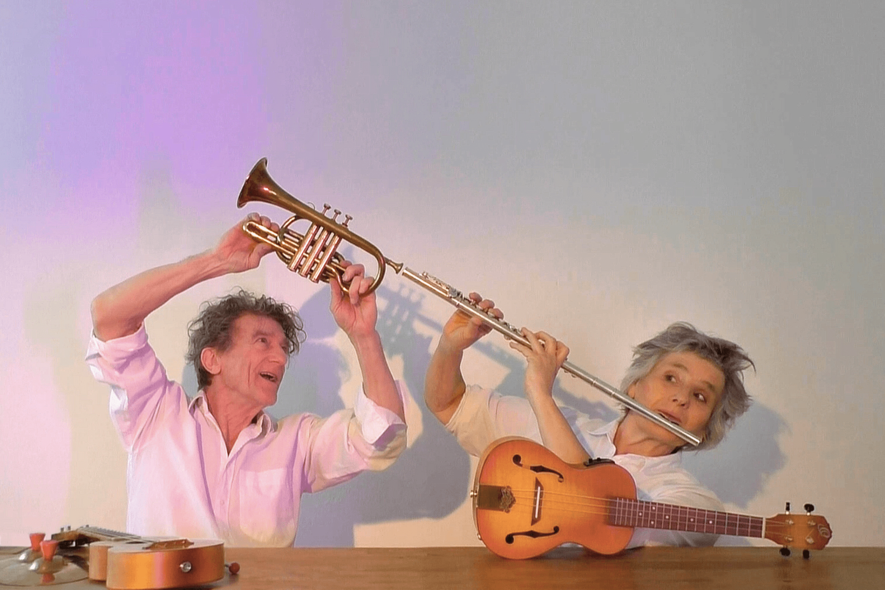 Zwei Performer:innen in weißen Hemden spielen mit Trompete, Flöte und Saiteninstrument.